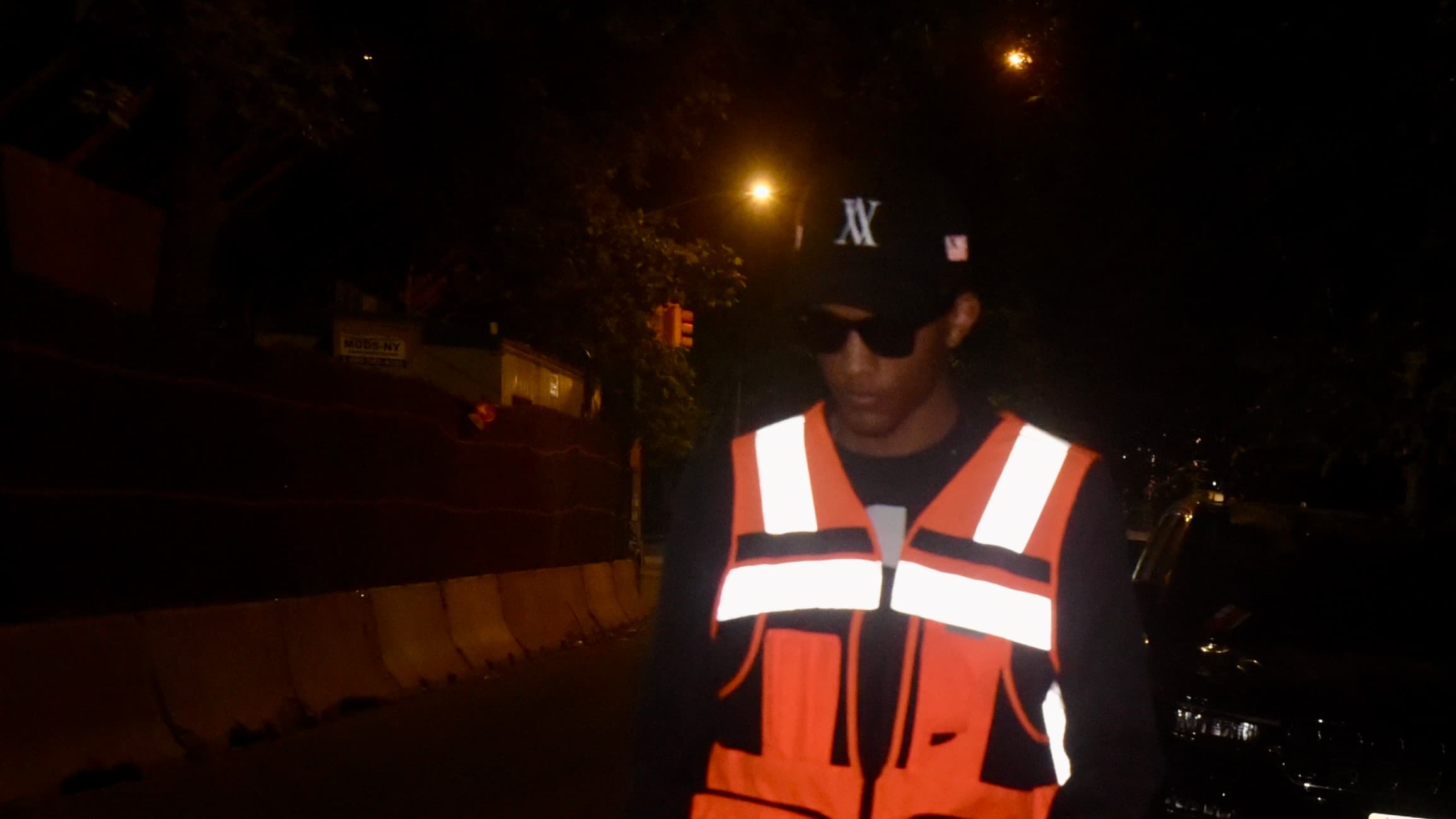 SNVRK at night in a hi-vis vest, its reflective tape lit by a camera flash