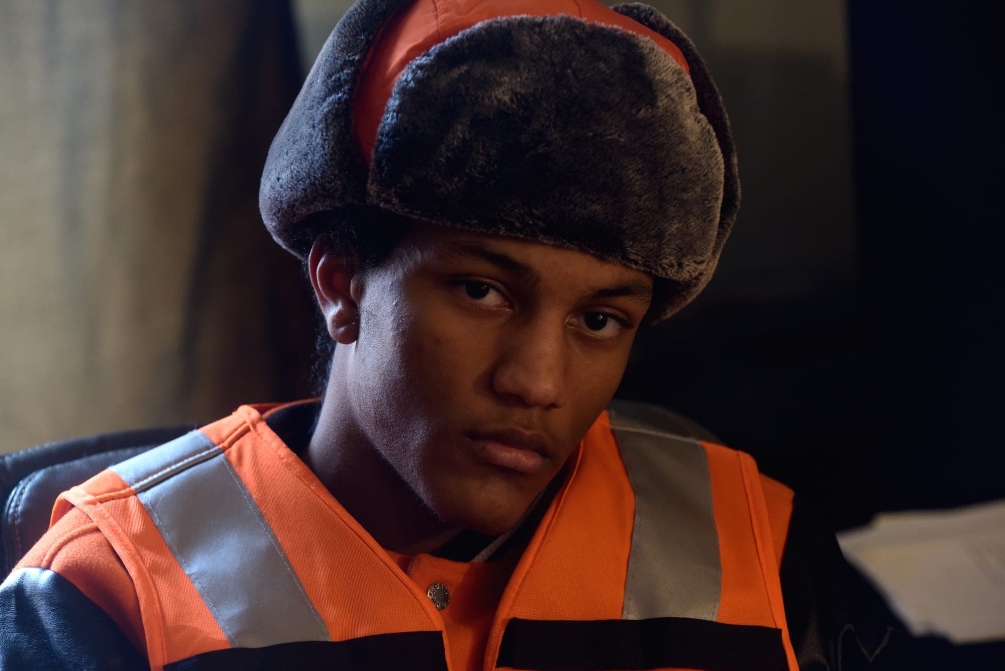 SNVRK in a fur trapper hat and hi-vis vest, looking into the camera
